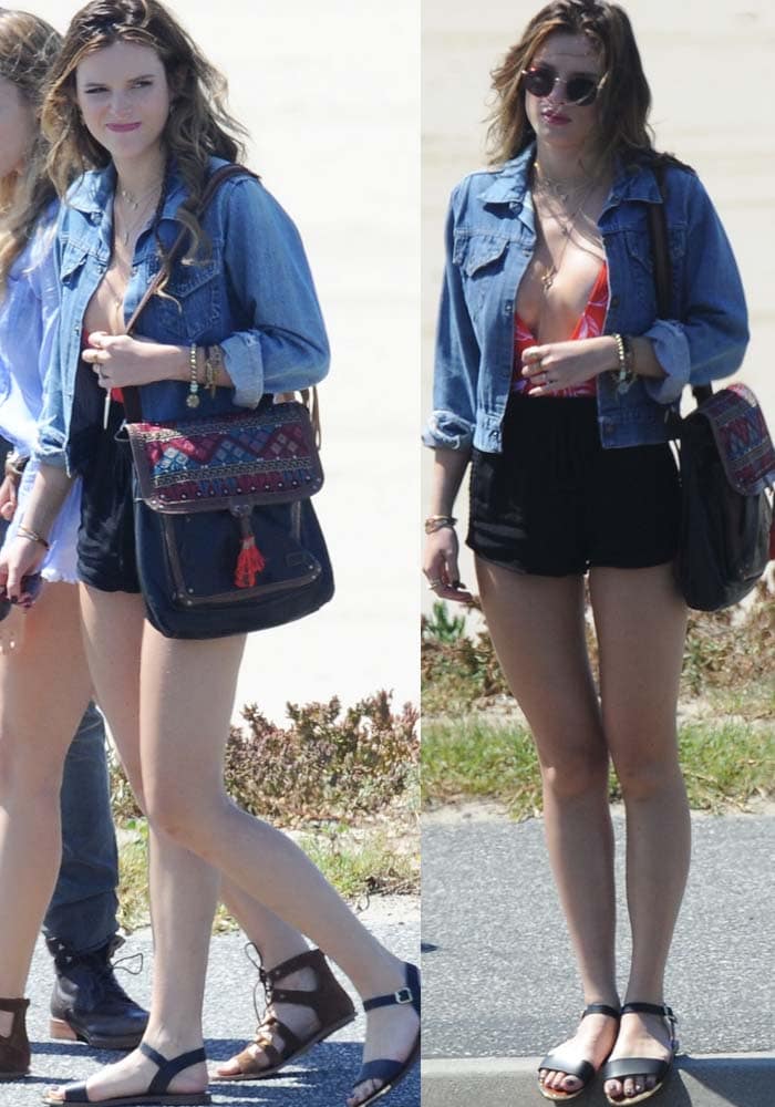 Bella Thorne wears a denim jacket and black shorts over a plunging swimsuit while filming on the beach